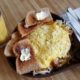 picture of a skillet of eggs, hashbrowns , toast and orange juice